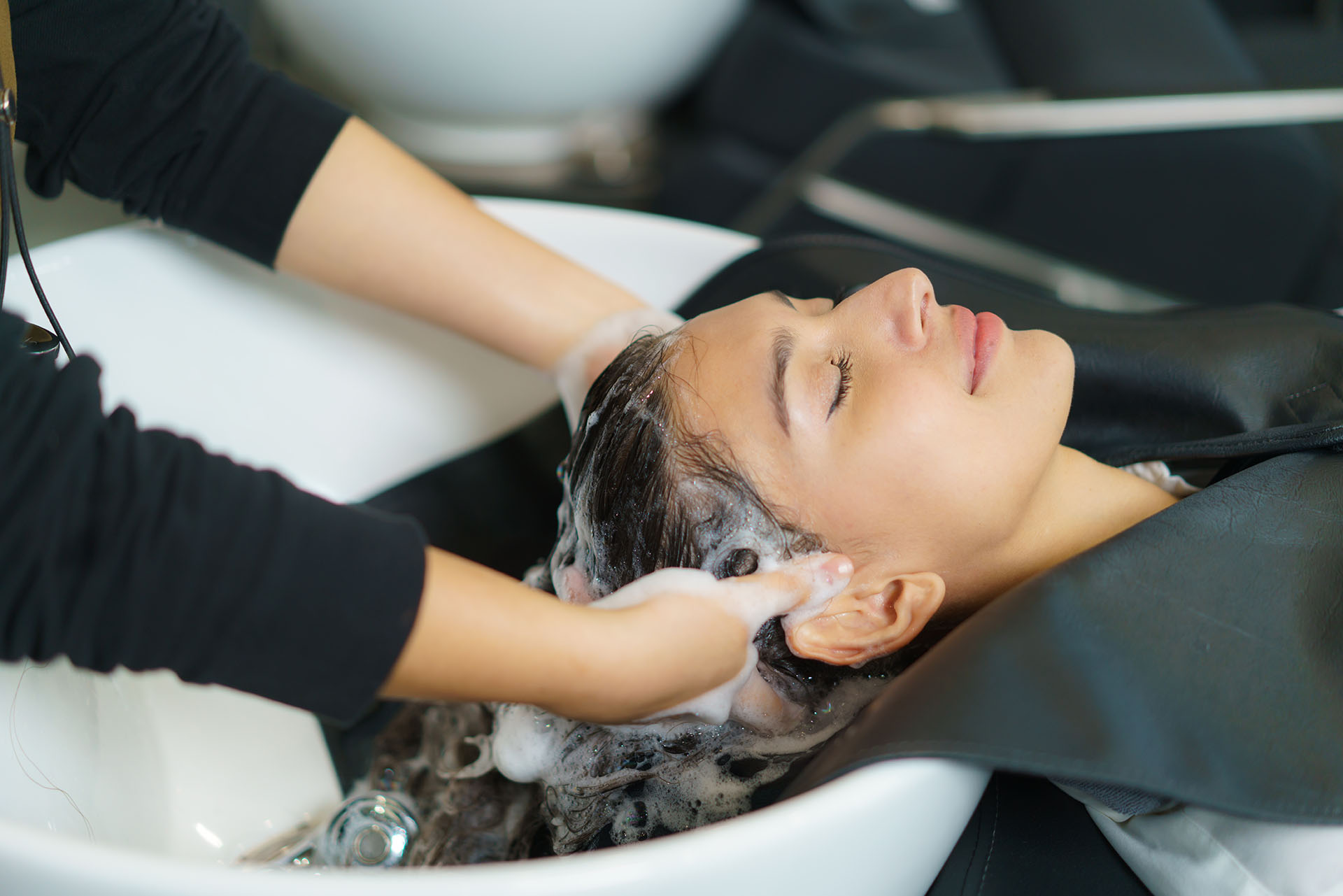 hairdresser is applying shampoo and massaging hair of a customer